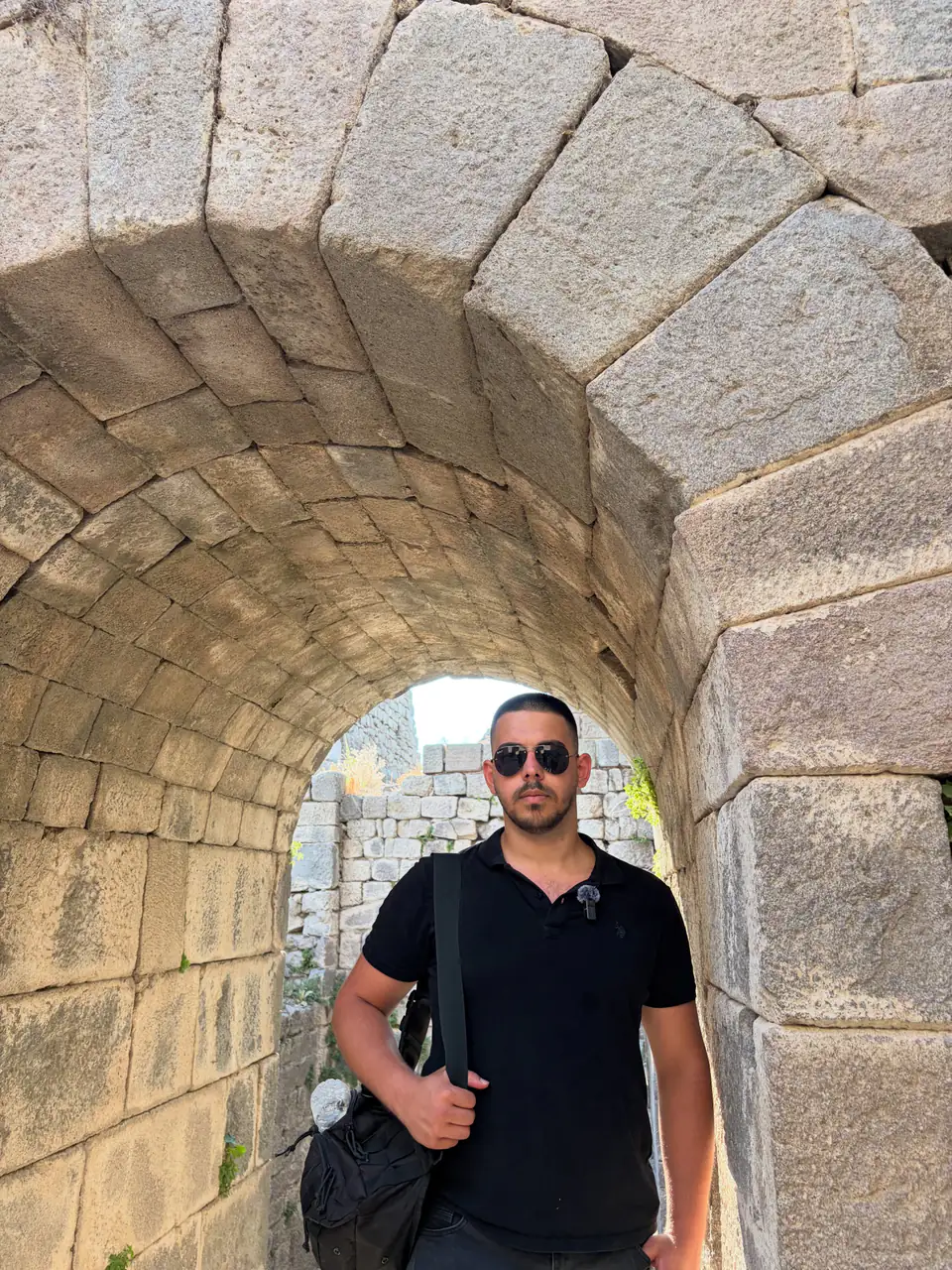 İlyas Saltay under an ancient stone arch
